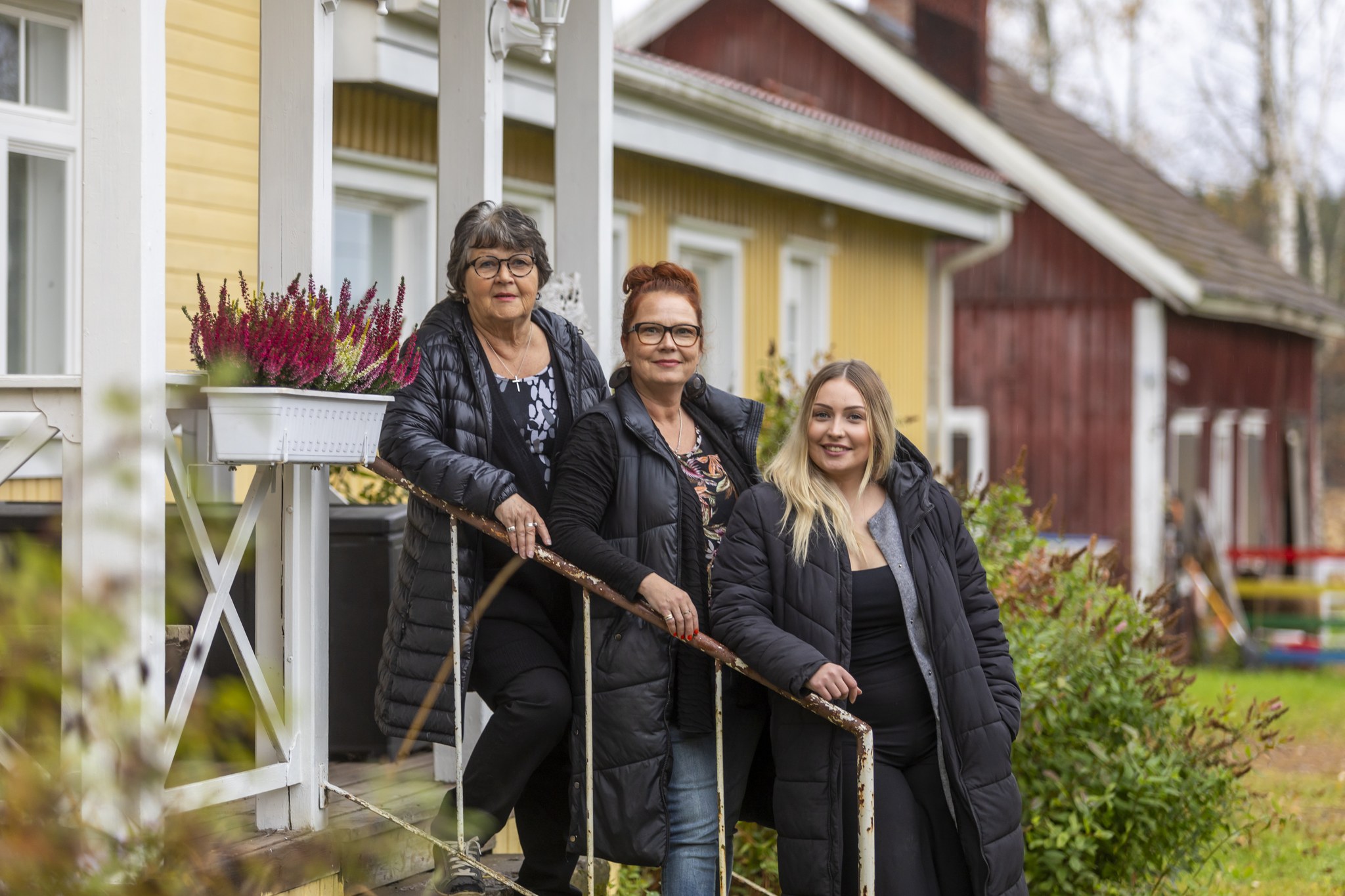 Riitta, Mia ja Ronja seisomassa talon portailla.