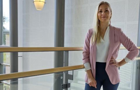 Henkilökuva Katja Mattilasta seisomassa kaiteen vieressä.