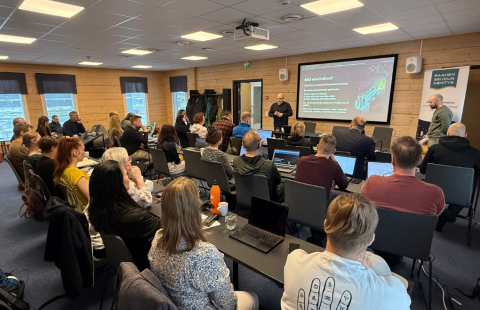 Työpajan osallistujat kuuntelemassa kouluttajia täydessä koulutustilassa.