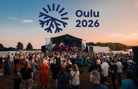 Konserttiyleisöä kesäisenä iltana Raahessa merenrannalla ja Oulu2026-logo.
