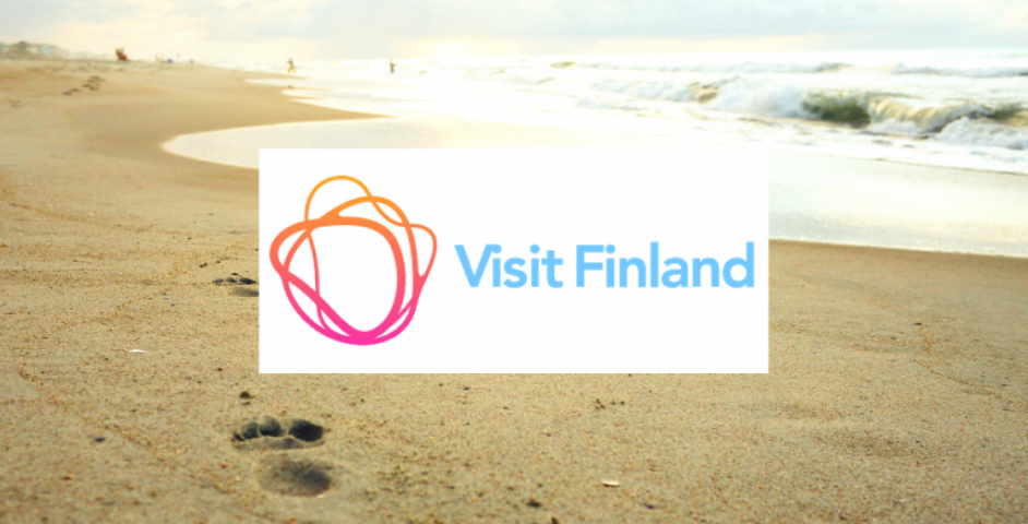 Visit Finlandin logo ja jalanjäljet rantahiekassa.
