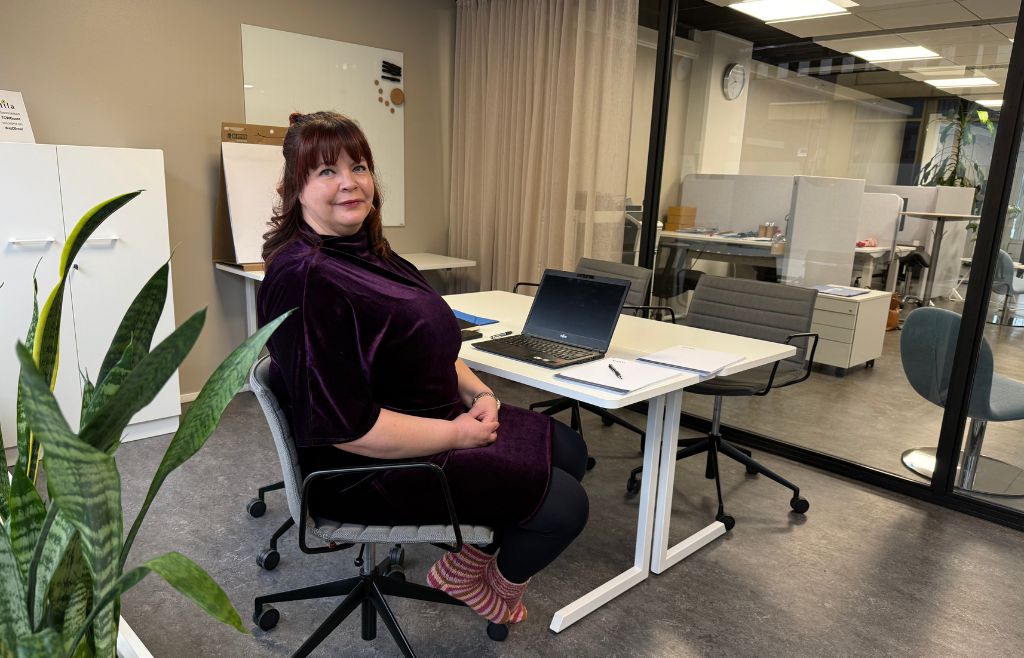 Marjaana istumassa toimistonsa työpisteellä.