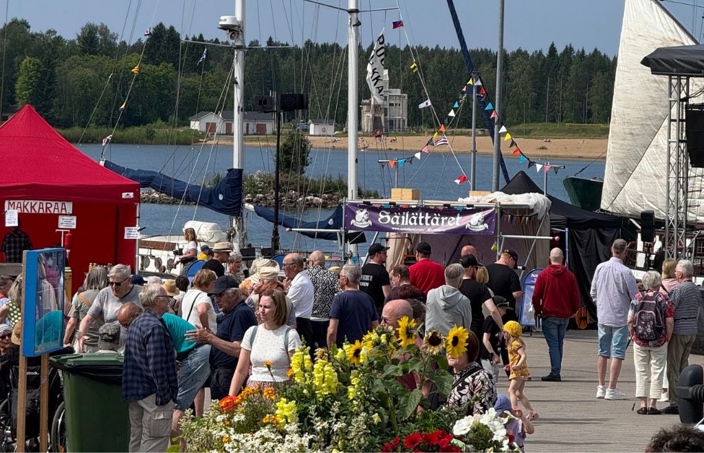 Markkinat käynnissä Raahen Rantatorilla. Kävijöitä, kukkaistutuksia ja taustalla meri.